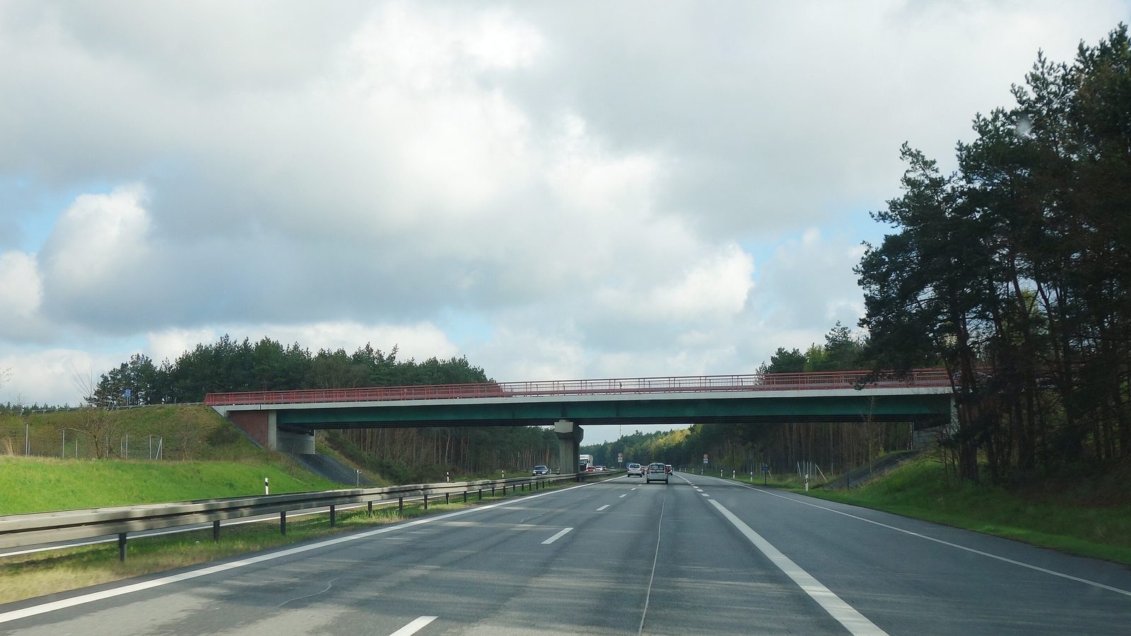 Zweispurige Autobahn A 24 bei Fretzdorf mit einer Brücke im Hintergrund und Kiefernwald am Rand